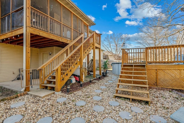 view of property exterior with a wooden deck, a sunroom, and a patio