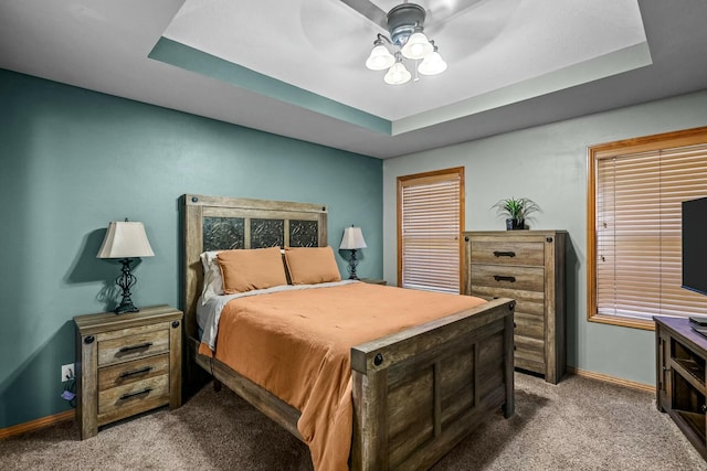 carpeted bedroom featuring ceiling fan and a tray ceiling