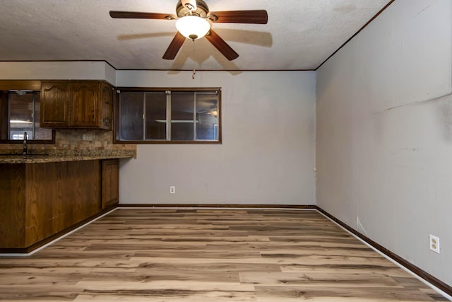 kitchen featuring decorative backsplash, sink, light hardwood / wood-style floors, and a textured ceiling