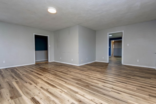 unfurnished room with a textured ceiling and light hardwood / wood-style flooring