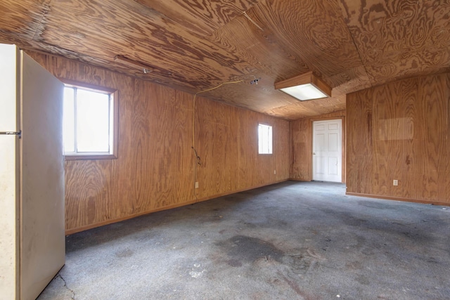 interior space with wooden walls, plenty of natural light, and fridge