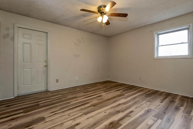 empty room with hardwood / wood-style floors, ceiling fan, and a textured ceiling