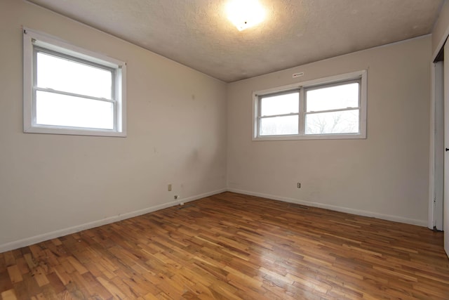 unfurnished room with hardwood / wood-style flooring and a textured ceiling