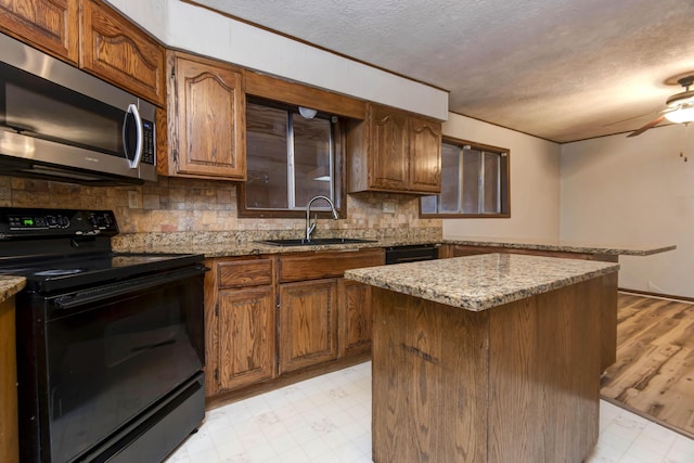 kitchen with a center island, black electric range oven, sink, light hardwood / wood-style flooring, and a textured ceiling