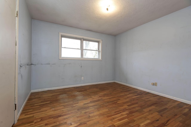 empty room with dark hardwood / wood-style flooring and a textured ceiling