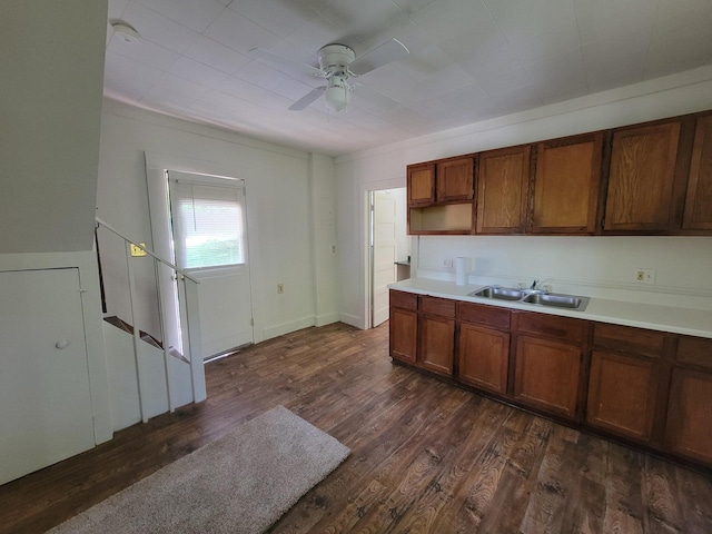 kitchen with a ceiling fan, brown cabinetry, dark wood-style floors, a sink, and light countertops