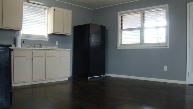 kitchen with white cabinets, black refrigerator, and sink