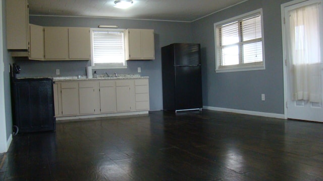 kitchen featuring cream cabinets, black fridge, a wealth of natural light, and sink