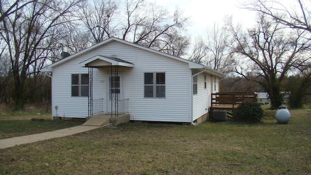 view of front of home with central AC unit and a front yard