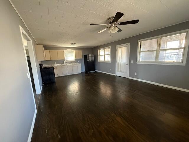 unfurnished living room featuring dark hardwood / wood-style floors and ceiling fan