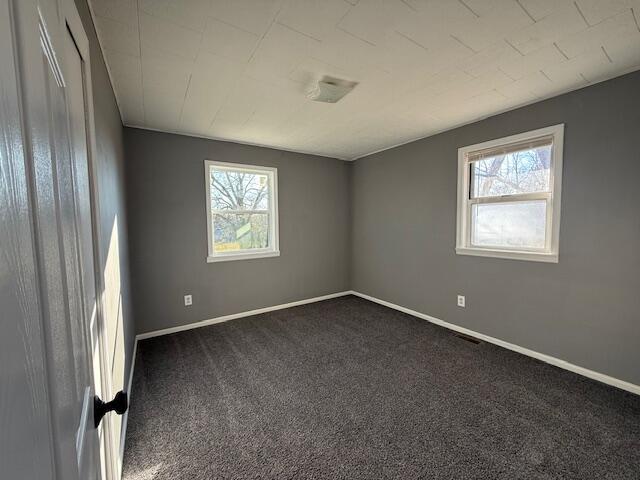 empty room featuring dark carpet and a healthy amount of sunlight