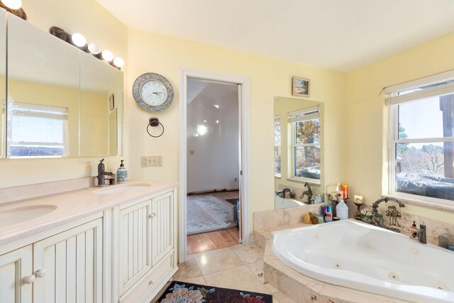 bathroom with tile patterned floors, vanity, a healthy amount of sunlight, and a relaxing tiled tub