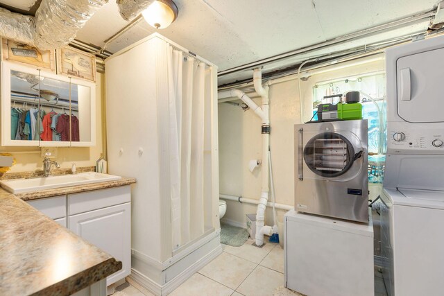 laundry room featuring stacked washer / drying machine, light tile patterned floors, and sink