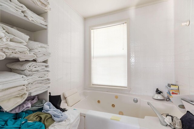 bathroom with a tub to relax in, a wealth of natural light, and tile walls