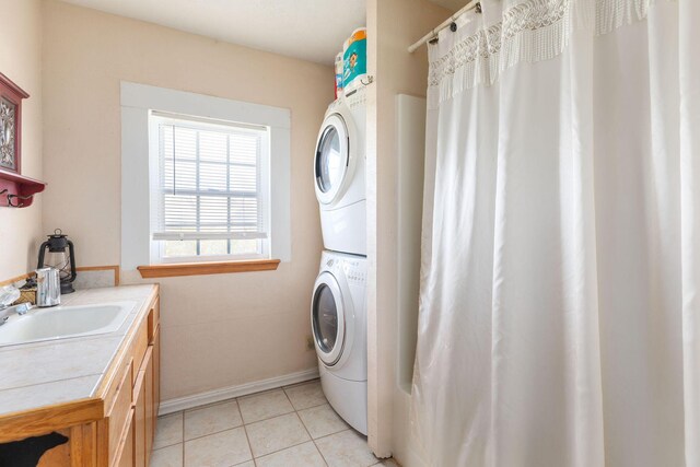 washroom featuring stacked washer / dryer, sink, light tile patterned flooring, and cabinets