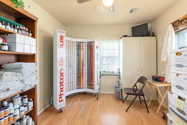 misc room with a textured ceiling, light hardwood / wood-style flooring, and ceiling fan