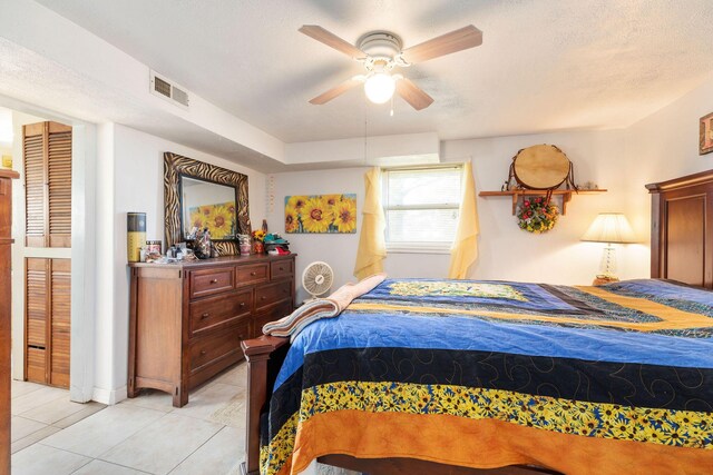 bedroom featuring ceiling fan, light tile patterned floors, and a textured ceiling