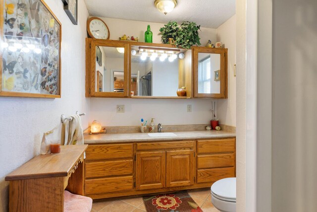 bathroom featuring tile patterned flooring, vanity, toilet, and a textured ceiling