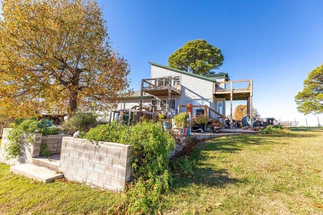 rear view of house with a lawn, a balcony, and a deck