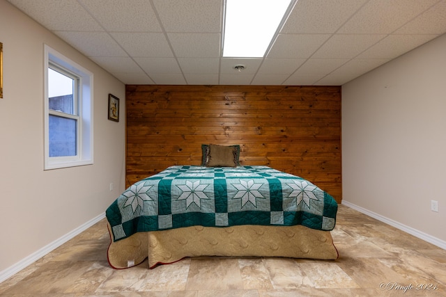 bedroom with a drop ceiling and wooden walls