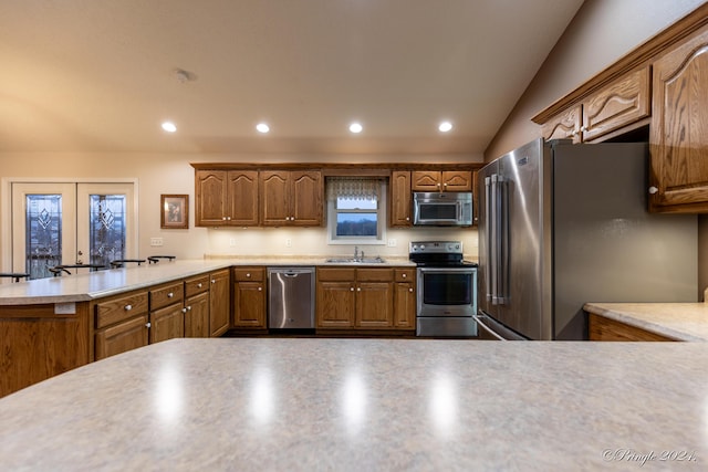 kitchen with kitchen peninsula, french doors, stainless steel appliances, vaulted ceiling, and sink