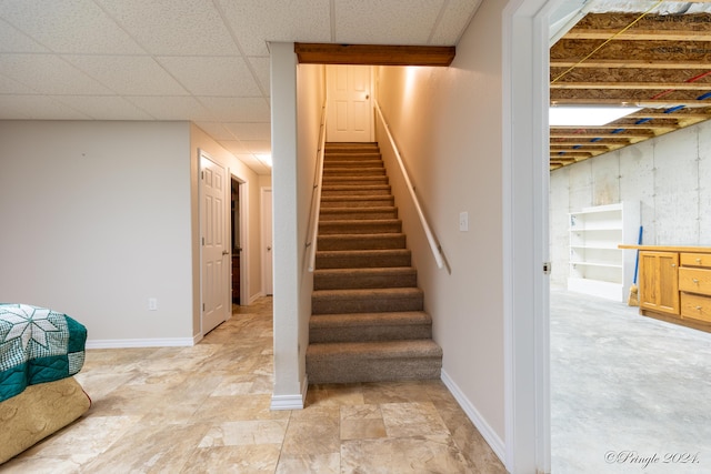 stairs with a paneled ceiling