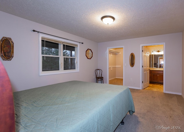 bedroom with connected bathroom, light carpet, a spacious closet, and a textured ceiling