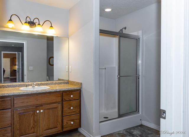 bathroom featuring a textured ceiling, vanity, and walk in shower