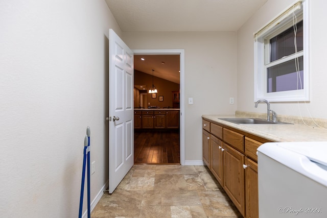 kitchen featuring light wood-type flooring, vaulted ceiling, sink, an inviting chandelier, and hanging light fixtures