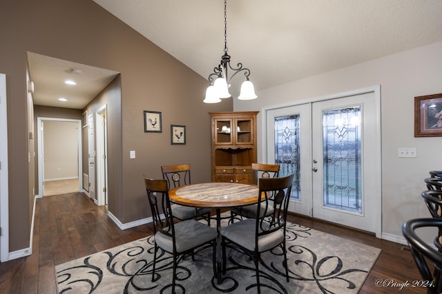 dining room with a notable chandelier, lofted ceiling, dark wood-type flooring, and french doors