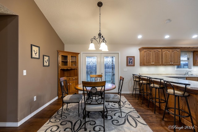 dining space with french doors, dark wood-type flooring, vaulted ceiling, and an inviting chandelier