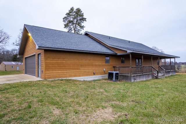 view of side of home featuring covered porch, a yard, a garage, and central AC unit