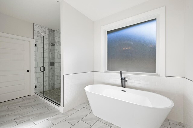 bathroom featuring plus walk in shower and tile walls