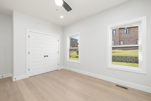 unfurnished bedroom featuring ceiling fan, a closet, and light wood-type flooring