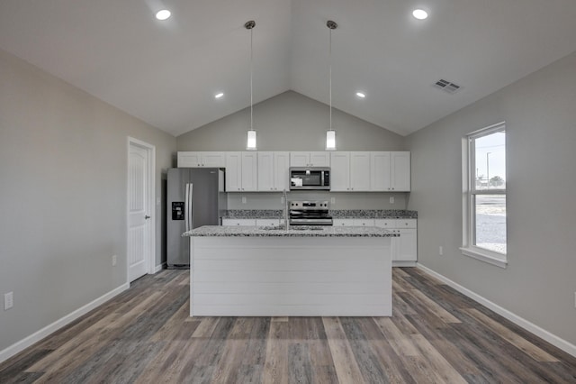 kitchen with pendant lighting, appliances with stainless steel finishes, white cabinetry, an island with sink, and light stone counters