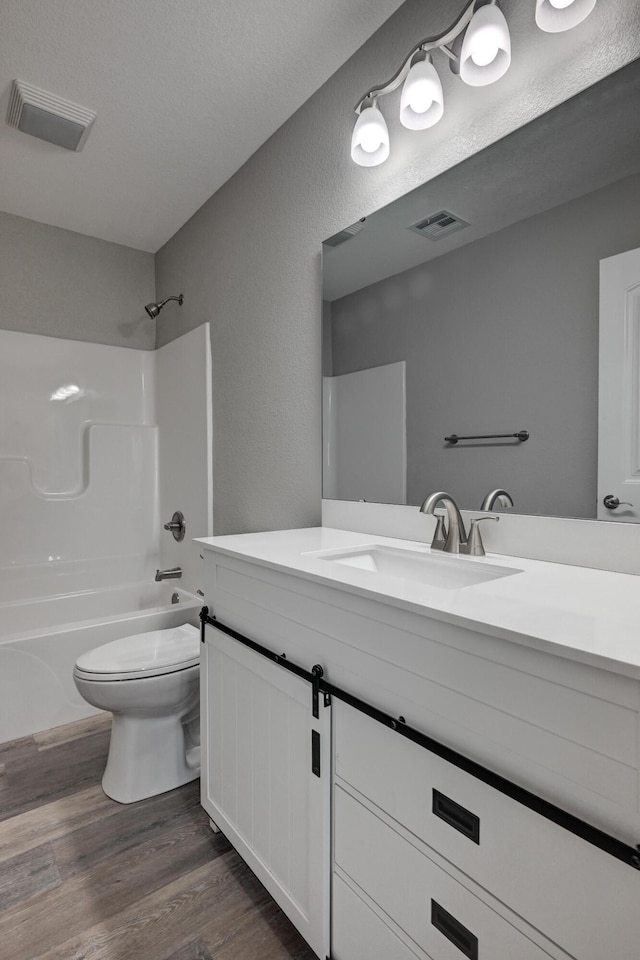 full bathroom with toilet, vanity, shower / bathing tub combination, wood-type flooring, and a textured ceiling