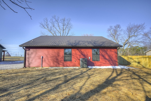 rear view of property featuring central air condition unit and a lawn