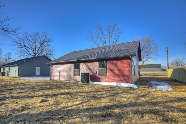 rear view of house featuring cooling unit and a lawn