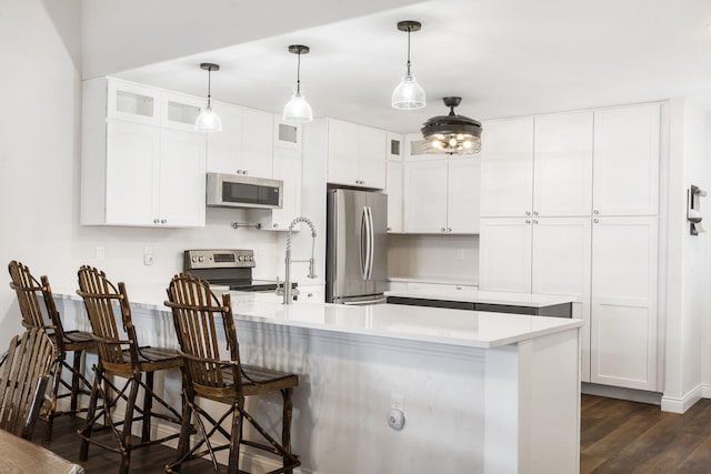 kitchen featuring a kitchen breakfast bar, white cabinetry, dark hardwood / wood-style floors, and appliances with stainless steel finishes