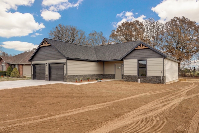 view of front of house with stone siding, an attached garage, concrete driveway, and a shingled roof