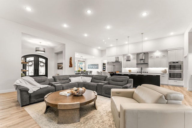 living room featuring light hardwood / wood-style flooring, french doors, and sink