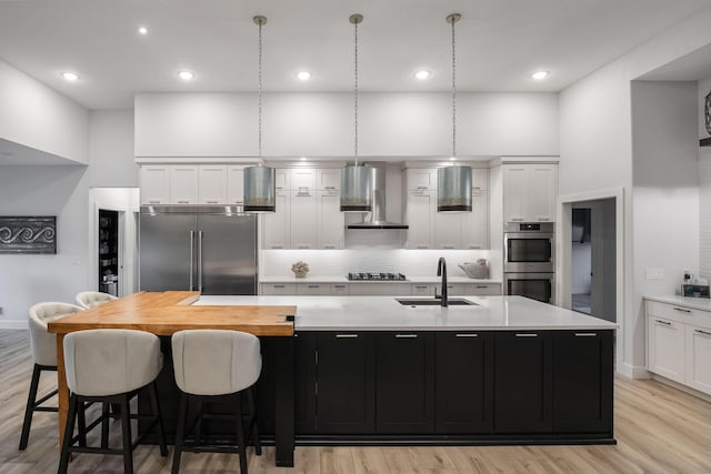 kitchen with white cabinets, a kitchen island with sink, sink, and appliances with stainless steel finishes