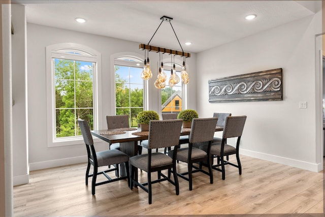 dining room with light wood-type flooring, an inviting chandelier, and plenty of natural light