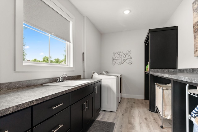 washroom featuring cabinets, light wood-type flooring, washing machine and clothes dryer, and sink