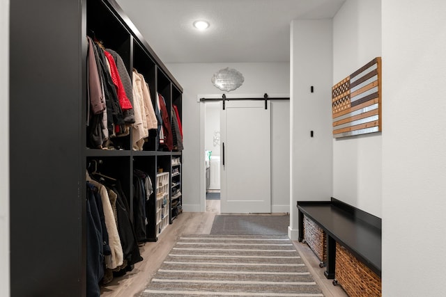 walk in closet with wood-type flooring and a barn door