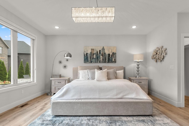 bedroom featuring light wood-type flooring and an inviting chandelier