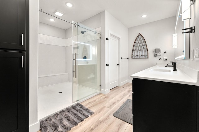 bathroom with hardwood / wood-style floors, vanity, and a shower with door