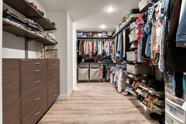 walk in closet with light hardwood / wood-style floors