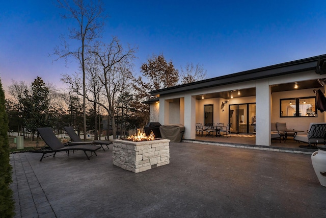 patio terrace at dusk featuring area for grilling and an outdoor fire pit