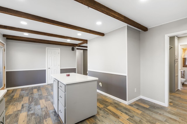 kitchen featuring a center island, dark wood-style flooring, light countertops, and beamed ceiling